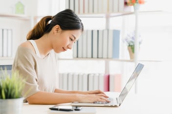 beautiful-young-smiling-asian-woman-working-laptop-desk-living-room-home