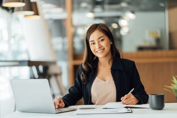 a businesswoman in front of her laptop, smiling