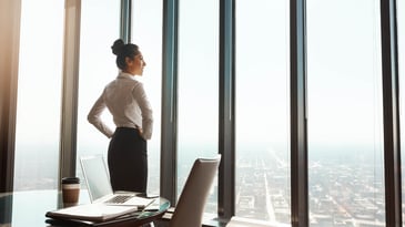 confident woman with her hands on her hips looking out the window