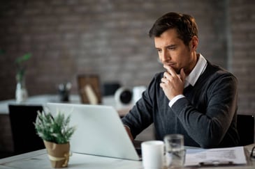 thinking businessman looking at his laptop