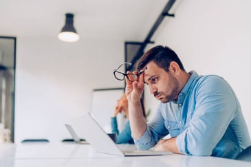 man staring at his laptop looking frustrated
