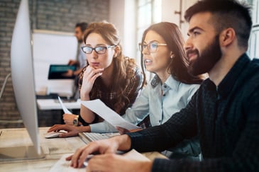 a team of professionals looking at a desktop monitor