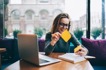 a happy woman holding a sticky note