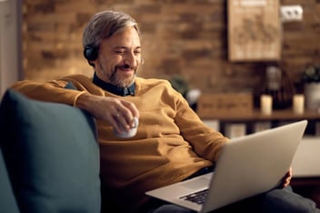 happy businessman drinking coffee and using laptop at home