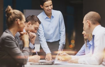 team meeting woman standing up pointing at a report