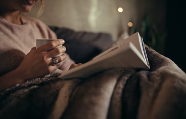 woman reading a book while holding a cup of coffee