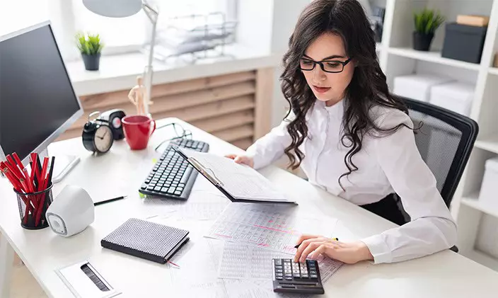 woman reading a report and using the calculator