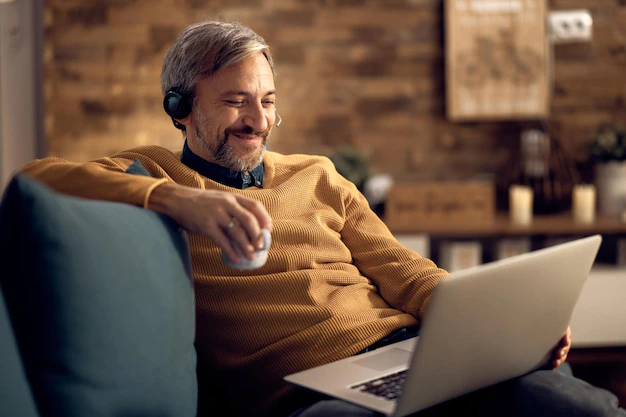 happy businessman drinking coffee and using laptop at home